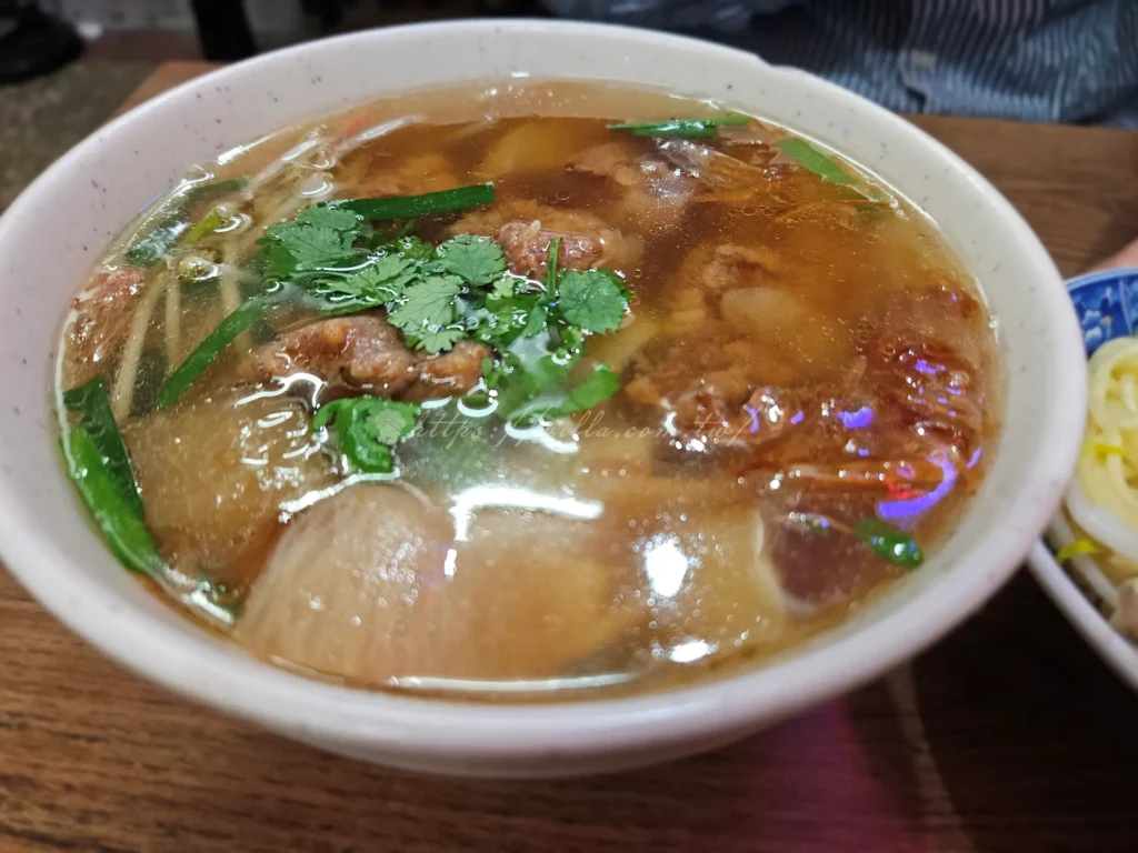 百年老店柴寮鯊魚煙排骨先炸後燉至入味,肉質軟嫩不柴,湯頭則以油蔥香與清甜為主,搭配彈牙的粄條,是在地人常點的美食組合。湯裡的白蘿蔔熬得透,帶出回甘的底味,滋味讓人回味。