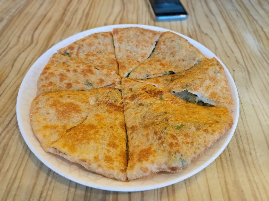 斗煥坪水餃館蔥油餅幾乎是每桌必點的招牌，也是老饕心中的鎮店之寶。口感介於傳統蔥油餅與炸蛋餅之間，外皮煎到金黃酥脆，酥香卻不乾硬，內裡保有濕潤麵香與蔥花，厚薄拿捏得恰到好處。