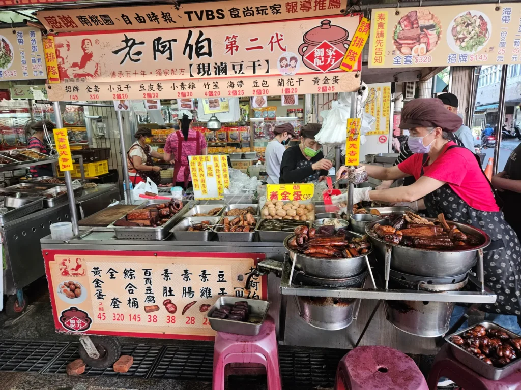 來到大溪沒吃過老阿伯，別說你來過老街！這間超人氣排隊名店以巨大的滷鍋同時熬煮各種食材。必點「招牌大盤」，內含黃金蛋、大豆干、素肚與素雞等。滷汁深層入味卻不重鹹，配上店家特製的靈魂辣椒醬與大量蔥花，口感層次極豐富。