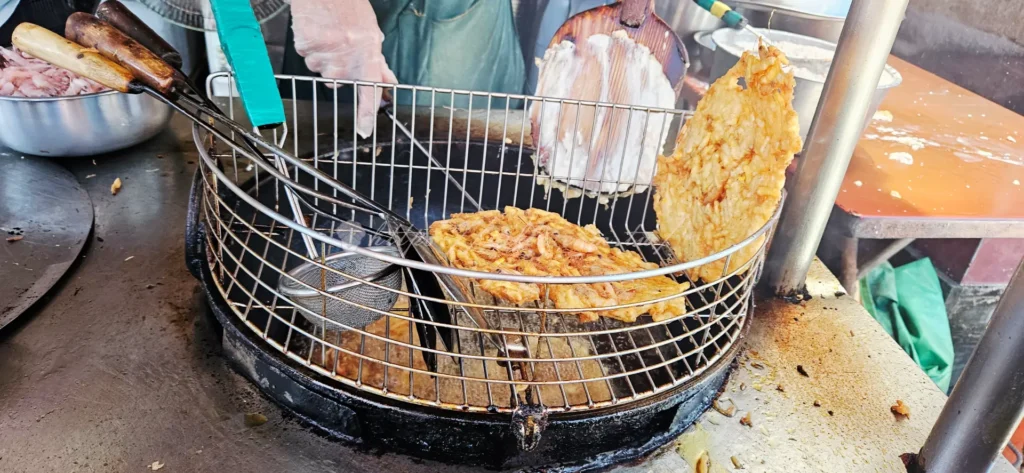 南方澳無名蝦餅蚵嗲蘿蔔糕！南方澳隱藏版的炸物小吃，製作過程非常療癒：先在圓鏟上鋪上一層厚厚的手切地瓜籤粉漿，接著毫不手軟地撒上大量新鮮的小溪蝦。