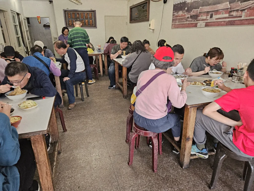 義排隊小吃金榜麵館每逢假日座無虛席的熱鬧座位區,饕客們正大口品嚐便宜大碗的客家麵食