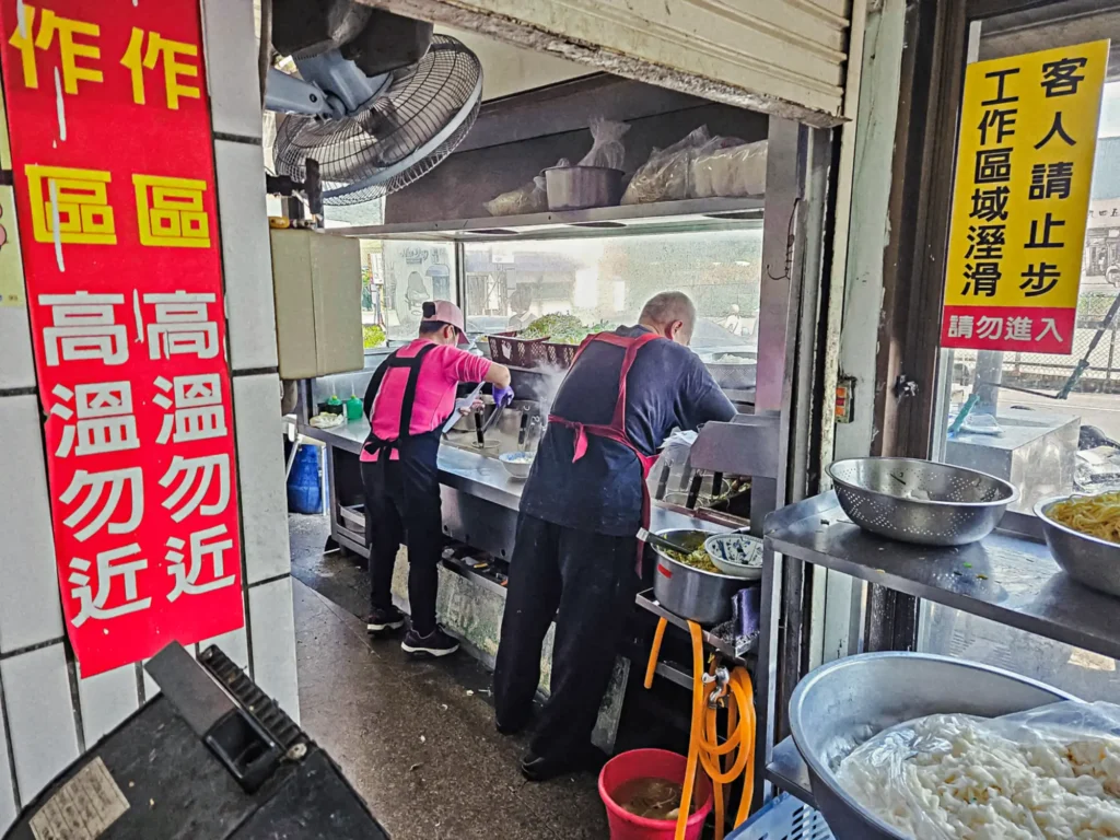 三義排隊小吃金榜麵館熱氣騰騰的開放式煮麵區,工作人員正忙碌地快速下麵出餐