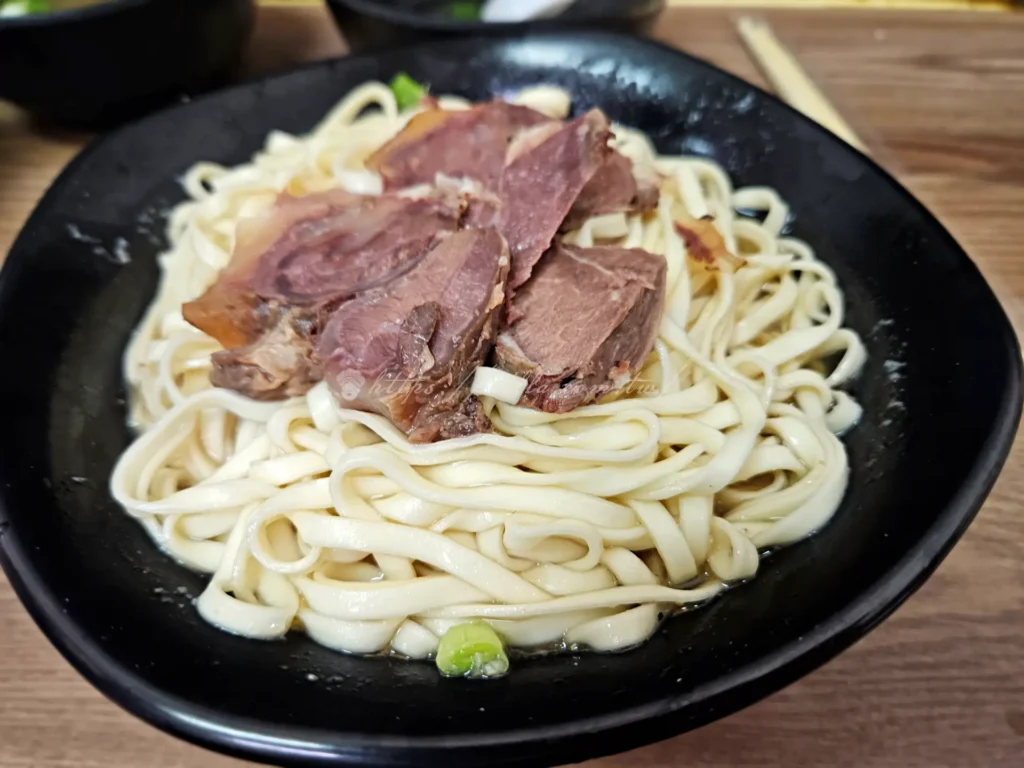 文化大學牛肉拌麵特寫，鋪滿牛肉片與濃郁蒜泥