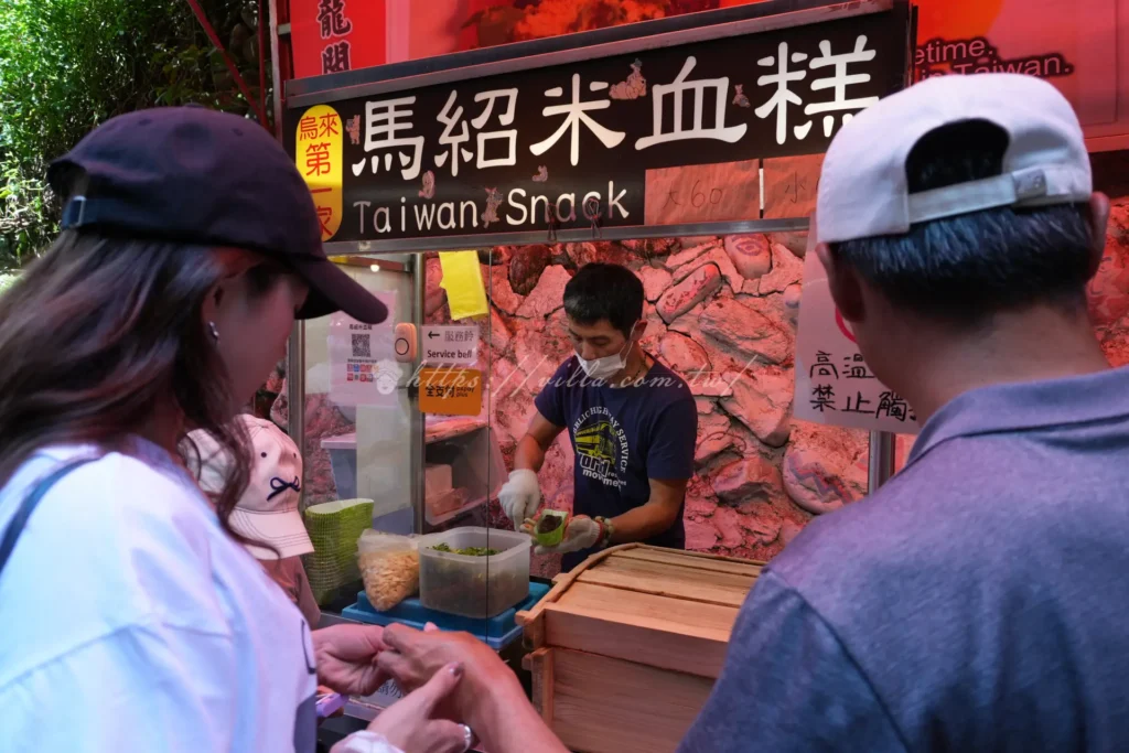 烏來老街排隊名攤馬紹米血糕，淋上花生粉醬汁搭配嗆辣蒜片