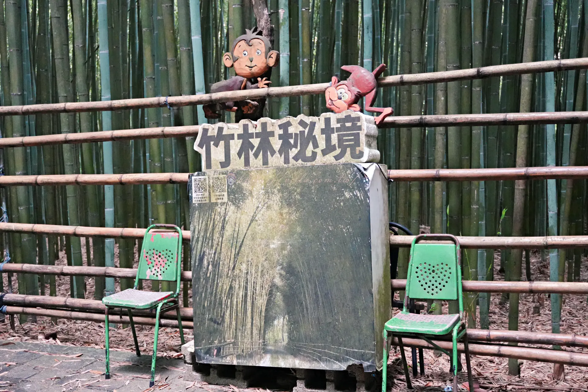竹林秘境石碑,兩側各擺一張綠色椅子,後方是竹柵欄